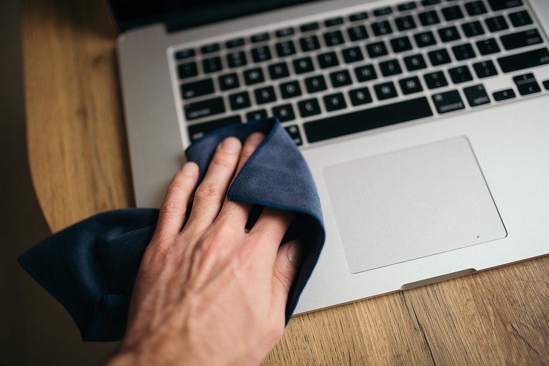 Man uses a cloth to clean his laptop.